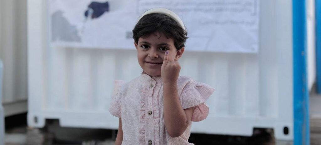 Imagen © UNRWA_Mohamed Hinnawi   Una niña muestra la marca en el dedo que indica que recibió la primera vacuna contra la polio en septiembre. (Archivo)